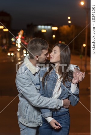 Young beautiful couple hugging on evening city background. Vertical frame Young beautiful couple hugging on evening city background. Vertical frame 88341505