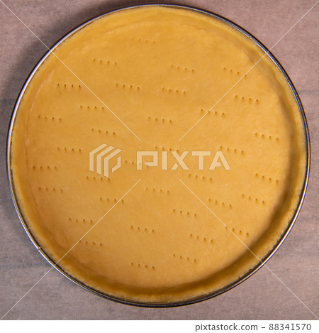 Metal fork makes holes in a raw pastry case in a metal baking tin 88341570