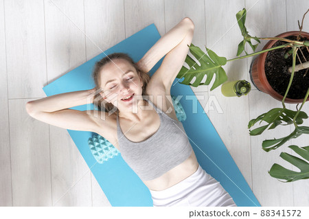 Beautiful relaxed healthy woman doing an exercise with foam roller on her back. Self myofascial massage at home 88341572