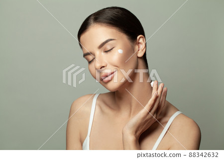 Head shot beautiful lady applying hydrating lotion creme on cheeks Head shot beautiful lady applying hydrating lotion creme on cheeks 88342632