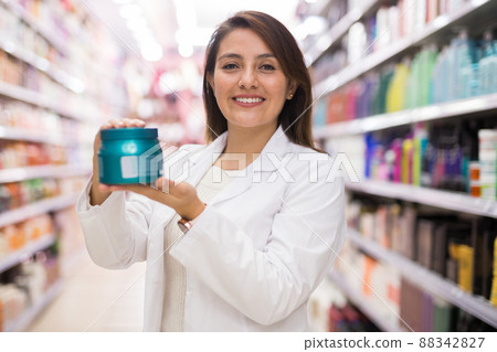 Smiling female seller demonstrating haircare cosmetics 88342827