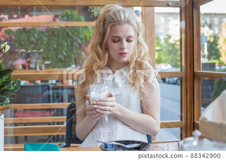 Serious young woman with an aromatic coffee in her hands Serious young woman with an aromatic coffee in her hands 88342900