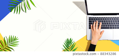 Person using a laptop computer with tropical leaves Person using a laptop computer with tropical leaves 88343286