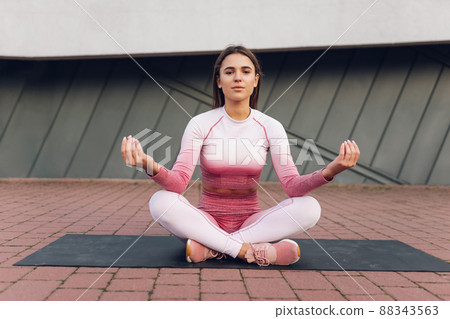 Girl in sportswear sitting in lotus position 88343563