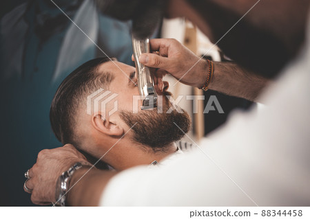 Barber makes a beard cut for a client Barber makes a beard cut for a client 88344458