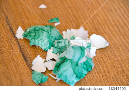 On a wooden table lies a colored shell from eggs. 88345203