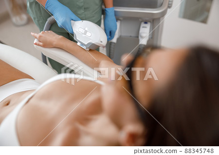 Closeup of hair removal procedure on arms with ipl machine from a professional cosmetologist 88345748