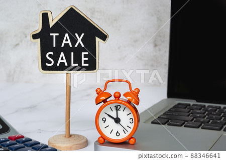 Tax sale text on wooden house model with on white table. Property tax concept. 88346641