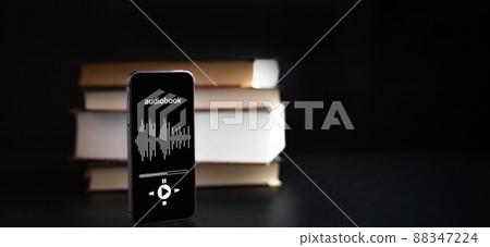 Audio book education. Phone screen with audio book app on paper books black background. Online learning, home school concept. Audio book education. Phone screen with audio book app on paper books black background. Online learning, home school concept. 88347224