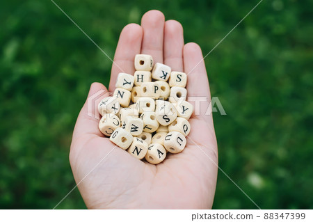 Wooden alphabet beads in a hand. Wooden alphabet beads in a hand. 88347399