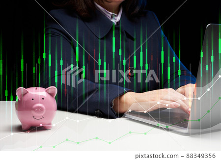 A woman in a suit sits at a table and works on a laptop, next to it is a ceramic piggy bank. Business indicators growth concept, enterprise analysis. A woman in a suit sits at a table and works on a laptop, next to it is a ceramic piggy bank. Business indicators growth concept, enterprise analysis. 88349356