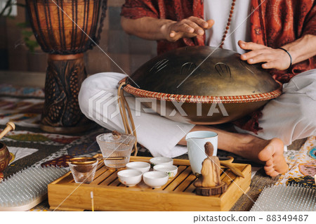 Close-up of a man's hand playing a modern musical instrument - the Orion tongue drum during the tea ceremony Close-up of a man's hand playing a modern musical instrument - the Orion tongue drum during the tea ceremony 88349487