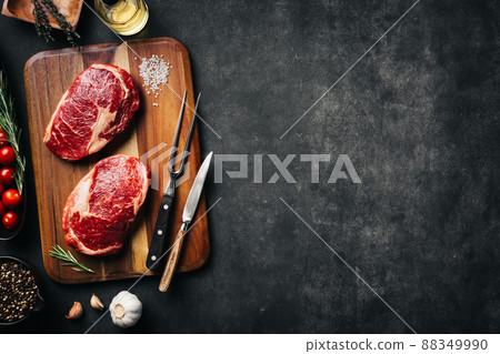 Raw beef steak with spices on cutting board. Dark stone background, top view scene with copy space 88349990