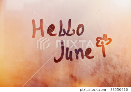 Handwritten text Hello June and flower shape on wet orange window Handwritten text Hello June and flower shape on wet orange window 88350416