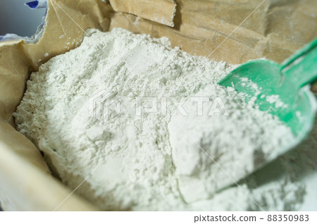 White plaster in an open paper bag. Finishing dry mixture for leveling walls and ceilings. Repair in the house with your own hands. DIY. Selective focus White plaster in an open paper bag. Finishing dry mixture for leveling walls and ceilings. Repair in the house with your own hands. DIY. Selective focus 88350983