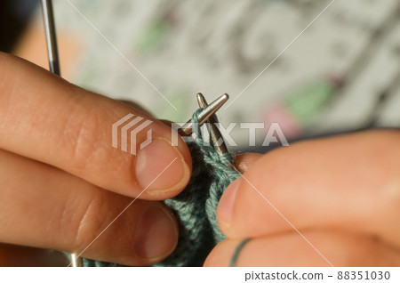 Close-up hand knitting. Hobbies, handicrafts. Knitting warm clothes from woolen fine yarn by hand on metal needles. Selective focus Close-up hand knitting. Hobbies, handicrafts. Knitting warm clothes from woolen fine yarn by hand on metal needles. Selective focus 88351030