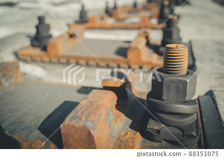 Fastening elements of railway rails to concrete sleepers. Seat rails on sleepers. Large rust bolt with nut. Selective focus 88351075