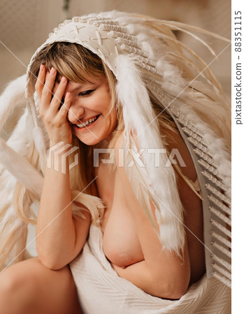 a nude happy blonde woman in a blanket in an Indian headdress of white feathers a nude happy blonde woman in a blanket in an Indian headdress of white feathers 88351115