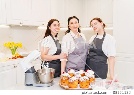 mother and daughters with Kraffins, easter cakes and Panettones in the kitchen. mother and daughters with Kraffins, easter cakes and Panettones in the kitchen. 88351123