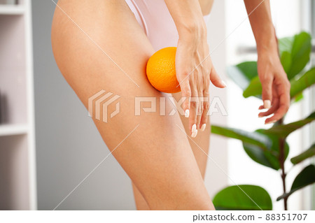 Cellulite problem, closeup view of slim woman in underwear with orange at home. Cellulite problem, closeup view of slim woman in underwear with orange at home. 88351707