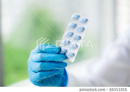 Closeup of female doctor holding pill for men health Closeup of female doctor holding pill for men health 88351858