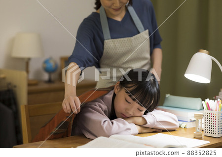 一位母親給在辦公桌前睡著的女兒蓋上毯子 88352825