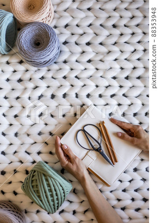 Closeup creative female hands holding elegant notepad surrounded by multicolored ribbon yarn Closeup creative female hands holding elegant notepad surrounded by multicolored ribbon yarn 88353948