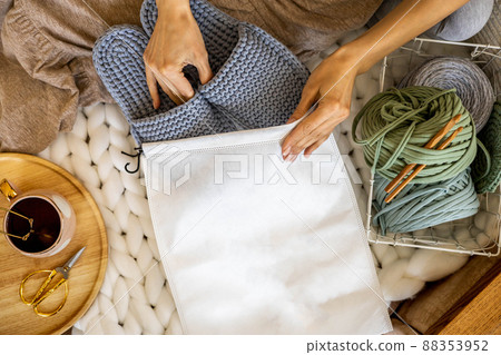 Woman designer hands packing handmade knitting ribbon yarn slippers into branding pack sending order Woman designer hands packing handmade knitting ribbon yarn slippers into branding pack sending order 88353952
