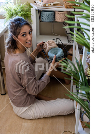 Happy blonde woman posing with ribbon yarn clews during seasonal cupboard tidying up home workplace Happy blonde woman posing with ribbon yarn clews during seasonal cupboard tidying up home workplace 88353956