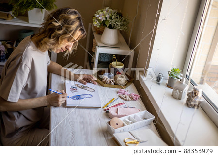 Creative woman clothes and shoes designer drawing colored sketch of slippers working at desk home 88353979
