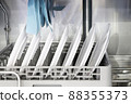 The automatic dishwasher with white clean dishes in basket .For restaurant. 88355373