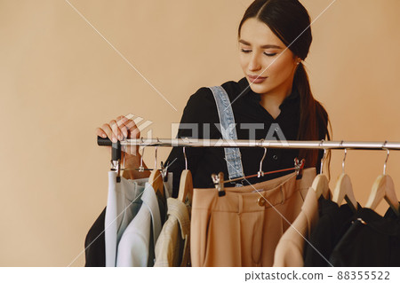 Woman on a brown background. Lady with clothes on a hanger. Woman on a brown background. Lady with clothes on a hanger. 88355522