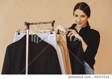 Woman on a brown background. Lady with clothes on a hanger. Woman on a brown background. Lady with clothes on a hanger. 88355524