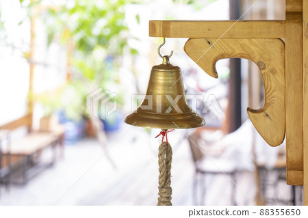 brass bell hand on to the wooden big plate stick on the pole wall. 88355650
