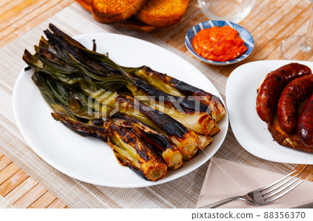 Calcot served on table with romesco sauce and botifarra 88356370