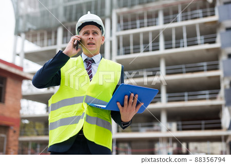 Engineer with laptop talking on phone outdoors Engineer with laptop talking on phone outdoors 88356794