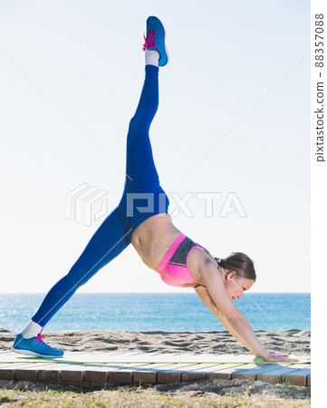 Girl stretching muscles on the sand Girl stretching muscles on the sand 88357088
