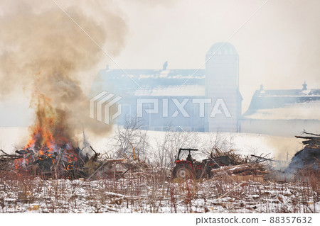 Tractor Moves Brush During a Controlled Burn on a Farm Property to Increase Arable Land Tractor Moves Brush During a Controlled Burn on a Farm Property to Increase Arable Land 88357632