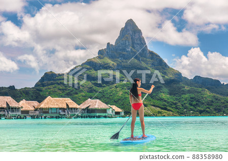 Tahiti Bora Bora island vacation recreational activity watersport woman paddleboarding on SUP Stand Up Paddle Board at luxury resort hotel in French Polynesia. Mt Otemanu summer holiday landscape Tahiti Bora Bora island vacation recreational activity watersport woman paddleboarding on SUP Stand Up Paddle Board at luxury resort hotel in French Polynesia. Mt Otemanu summer holiday landscape 88358980