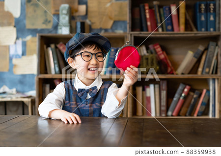 一個微笑的男孩看著他的錢包 一個微笑的男孩看著他的錢包 88359938