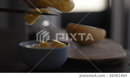 add fresh mango to yogurt in bowl 88361464