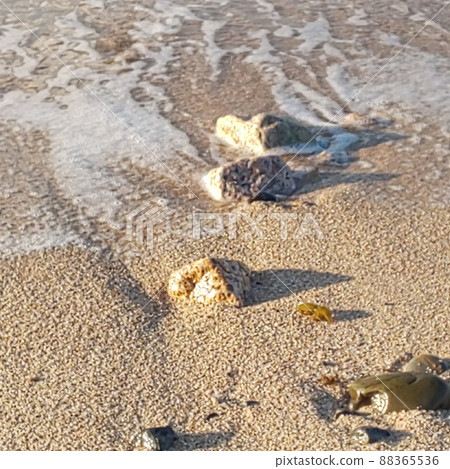 It is a photograph of pebbles and waves that had fallen on the sandy beach. It is a photograph of pebbles and waves that had fallen on the sandy beach. 88365536