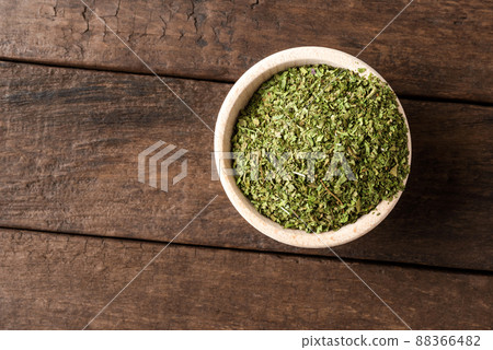 Dried lovage leaves in bowl on wooden table. Close up. Top view 88366482