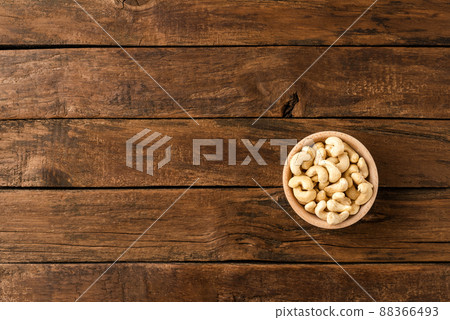Roasted cashews in bowl on wooden table. Top view 88366493