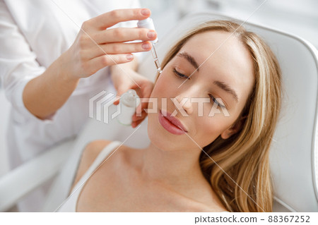 Female cosmetologist applying vitamin serum on woman face Female cosmetologist applying vitamin serum on woman face 88367252