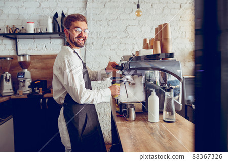 Cheerful male barista using coffee machine in cafe 88367326