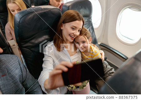 Happy mother and daughter making selfie in airplane Happy mother and daughter making selfie in airplane 88367375