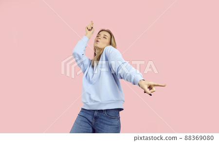 Happy beautiful young woman enjoying music and dancing isolated on pink background 88369080