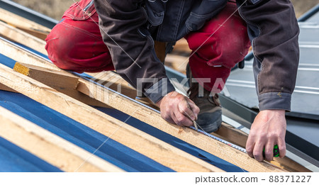 Craftsman or construction worker install a new roof, roofing tools, new metallic roof or metal sheet, building concept 88371227