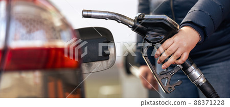 Female worker hand holding nozzle fuel fill oil into car tank at a pump gas station, For the concept transportation power business technology concept Female worker hand holding nozzle fuel fill oil into car tank at a pump gas station, For the concept transportation power business technology concept 88371228